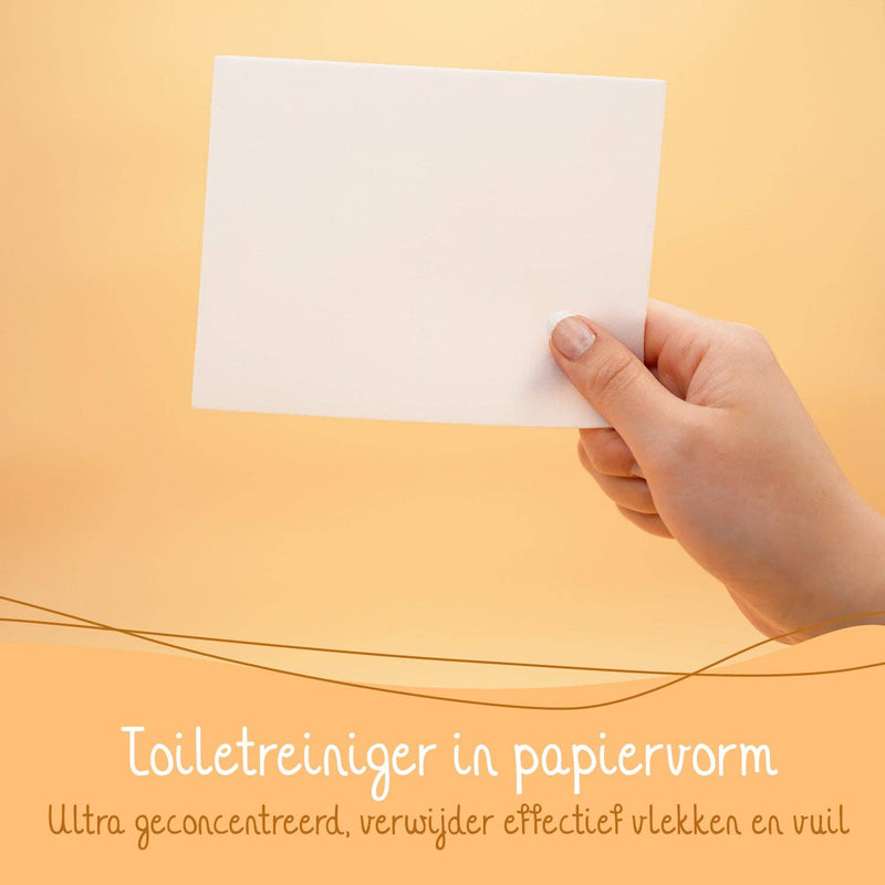Eine Hand hält ein weißes Toilettenreinigungsblatt, mit niederländischem Text "Toiletreiniger in papierform Ultra geconcentreerd, verwijdert effectief vlekken en vuil" (Toilettenreiniger in Papierform Ultra konzentriert, entfernt effektiv Flecken und Schmutz).