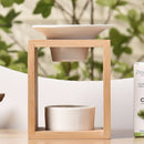 Eine Aromalampe aus Holz mit einer weißen Keramikschale und einem Teelichthalter, die neben einer Schachtel Zedernholz-Ätherisches Öl steht.