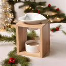 Eine Aromalampe aus Bambusholz mit einer herzförmigen Keramikschale, präsentiert in einem weihnachtlichen Dekor mit Tannenzweigen, Lichterketten und roten Kugeln.