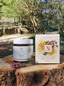 Tiegel und Schachtel der Heidehonig-Feuchtigkeitscreme (Mel de Urze) auf einem Baumstumpf im Freien.