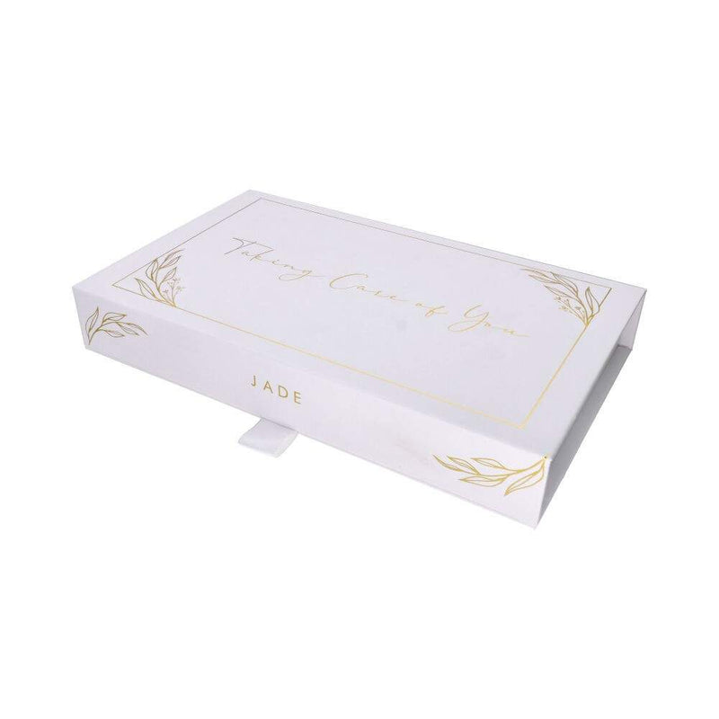Weiße Geschenkbox für Jade-Gesichtsmassager, mit Goldblatt-Design und "Taking Care of You" Aufschrift.