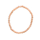 Ein kreisförmiges Perlenarmband aus einheitlichen, runden pfirsichfarbenen Steinen.