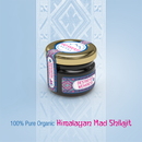 Ein Glas Himalaya Mad Shilajit mit goldenem Deckel auf blau gemustertem Hintergrund.