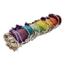 Ein Salbei-Smudge-Stick, verziert mit bunten Regenbogen-Rosenblättern und lila Blüten, gebunden mit weißem Faden.