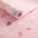 Eine Makro-Nahaufnahme einer rosa Yogamatte mit Terrazzo-Muster, die das geprägte „myga“-Logo und die gerippte, rutschfeste Oberflächenstruktur zeigt.