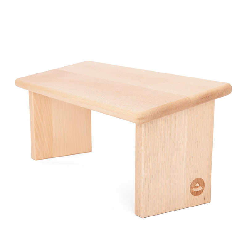 Meditationsbank aus hellem Holz mit glatter rechteckiger Sitzfläche und zwei vertikalen Beinen, auf weißem Hintergrund.