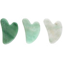 Drei herzförmige Gua Sha Massagesteine aus grünem Aventurin in verschiedenen Grüntönen, von dunkel bis hell, poliert auf weißem Hintergrund.