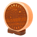 Eine runde, geschnitzte Salzlampe mit einem Mondphasen- und Stern-Design in einer Seitenansicht auf einem dunklen Holzsockel.