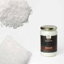  Ein Glas Kokosnussöl (Oleum Cocos nucifera) der Marke Ölwerk steht rechts auf weißem Hintergrund, umgeben von einem Haufen weißer, geriebener Kokosnuss oben links und einem Block festen Kokosöls unten links. Das Etikett bewirbt das Produkt als „feinste biologische Öle“ und „100% rein & naturbelassen“.