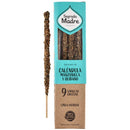 ein Stäbchen grobes Kräuter-Räucherwerk neben seiner zweifarbigen Kartonverpackung (Türkis und Braun). Das Produkt ist Sagrada Madre CALÉNDULA MANZANILLA Y OLÍBANO (Ringelblume, Kamille und Weihrauch) Räucherwerk, das 9 dicke Stäbchen enthält und als 100% natürlich gekennzeichnet ist.