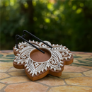 Ein lotusförmiger Salbeibrenner aus Holz mit weißem Muster auf einem Steintisch im Freien.