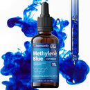 Eine Flasche Harmonify Methylenblau USP Grade 1% Flüssiglösung mit einer Pipette, die blaue Flüssigkeit in dynamische blaue Farbspritzer abgibt, um die Reinheit und Wirksamkeit des Produkts zu visualisieren.