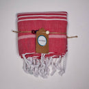 Ein gefaltetes rot-weiß gestreiftes Handtuch mit weißen Quasten und einem ECOBAIN-Markenetikett.