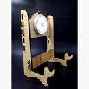 Ein zusammengebauter, lasergeschnittener hölzerner Display-Ständer (Halterung) für runde Objekte wie Ornamente oder Medaillen, mit verstellbarer Rückseite und einem leeren weißen ringförmigen Scheibenstück, das oben befestigt ist, aus einem Seitenwinkel gesehen.