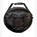 Eine runde, schwarze Tragetasche mit Reißverschluss für eine Trommel, ausgestattet mit einem gepolsterten Schultergurt, einem Tragegriff und einer Vordertasche mit dem weiß gestickten Logo "inner Rhythm".