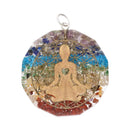 Ein kreisförmiger Orgon-Anhänger mit einer goldenen meditierenden Figur über geschichteten Steinen in Chakra-Farben.