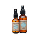 Zwei braune Glas-Sprühflaschen unterschiedlicher Größe, etikettiert mit „PAAVANI pitta COOLING AROMATHERAPY SPRITZER“ und einem blauen geometrischen Muster.