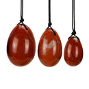 Ein Set aus drei polierten roten Jaspis Steineiern in verschiedenen Größen, die jeweils an einer schwarzen Schnur hängen.
