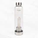 Eine transparente Wasserflasche der Marke "myga" mit einem klaren Quarzkristall im Inneren, stehend auf einer weißen Marmoroberfläche.