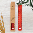 Roter Räucherstäbchenhalter „Elm“ aus Holz mit silbernen Mondmotiven neben der Verpackung und Räucherstäbchen.