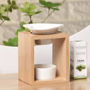 Eine Aromalampe aus Bambusholz mit einer weißen Keramikschale, auf einem Tisch neben einer Schachtel Zen Arôme Zedernholz ätherisches Öl.