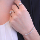 Eine Frau, die zwei silberne Diamantringe und ein funkelndes Diamant-Tennisarmband trägt.