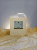 Großer transparenter Kunststoffkanister mit Traubenkernöl auf goldenem Tuch.