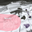 Verschiedene Steinmassager, darunter Jade- und Amethyst-Roller sowie Gua Sha Steine, zusammen mit ihren Geschenkboxen auf weißem Stoff. Der Text hebt hervor, dass diese Werkzeuge die Durchblutung verbessern und die Kollagenproduktion anreg