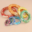 Eine Gruppe bunter, gemusterter, ringförmiger Klangschalenkissen ineinander verschlungen.