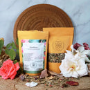 Zwei Packungen MenoPeace Kräutertee, umgeben von rosa und weißen Rosen.