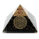 Eine Pyramide aus schwarzen Steinen und Metallspänen mit einem goldenen, geometrischen Muster.