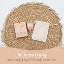 Eine Bamboozy Menstruationstasse (Größe M) und ihre umweltfreundliche Verpackung, einschließlich eines Tragebeutels, auf einer geflochtenen Matte präsentiert, hervorhebend, dass das Paket durch den Briefkasten passt.