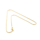 Dünne goldene Schlangenkette auf weißem Hintergrund.