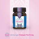 Ein Glas Himalaya Mad Honey auf rosafarbenem Hintergrund mit traditionellen Mustern.