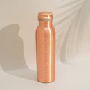 Eine schlichte Kupferwasserflasche, graviert mit den sieben Chakra-Symbolen, unter sanftem Licht.