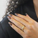 Die Hand einer Frau, die einen goldenen Diamant-Verlobungsring mit gedrehter Ringschiene trägt.