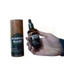 Dunkelbraune glasflasche mit schwarzem tropfverschluss und feels supreme agaricus blazei pilz flüssigergänzung neben holzbehälter
