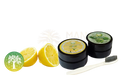 Zwei schwarze zylinderförmige behälter naturzahnpulver ancient purity tooth lemon und peppermint mit frischen zitronen und minzblättern