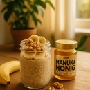 Glas mit ANUK Honey Manuka-Honig MGO250, cremige Textur, goldgelbe Farbe, auf einem Holztisch, Nahaufnahme