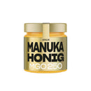 Glas mit ANUK Manuka-Honig MGO250 von ANUK Honey, cremiger Honig mit goldener Farbe und Honigwaben im Hintergrund