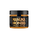 Glas mit ANUK Honey Manuka-Honig MGO400+ in goldener Farbe, Honig-Produkt in einer transparenten Glasdose, Nahaufnahme