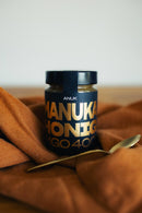 Glas mit ANUK Manuka-Honig MGO400+ in goldener Farbe, cremige Textur, Honig mit hochwertiger Manuka-Qualität.
