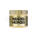 Ein goldener glasbehälter mit anuk manuka-honig mgo250, metallischem deckel und label mit schwarzem text