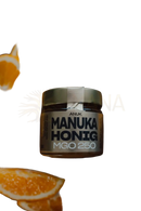 Ein glas anuk manuka-honig mgo250 mit metallverschluss und label mgo 250 umgeben von orangenscheiben hochwertiger premium-honig
