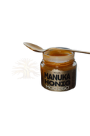 Ein glas anuk manuka-honig mgo250 mit dunklem braunem etikett und goldenem honig im premium-honig glas