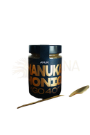Ein elegantes schwarzes glas anuk manuka honey mgo400+ mit goldenen schriftzügen auf warmem stoff bei the mana shop