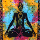 Ein buntes Tie-Dye-Wandtuch mit der schwarzen Silhouette einer im Lotussitz meditierenden Person und den sieben Chakra-Symbolen.