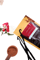 Eine packung ayamani love choc aphrodisierende heisse schokolade mit rohem kakao und zwei schwarzen vanilleschoten auf holzoberfläche