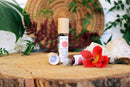 Ätherisches Balancierendes Wurzel-Chakra-Öl von Ayamani Naturals mit Kräutern und Kristallen, Flasche auf natürlichem Hintergrund