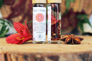 Ätherisches Balancierendes Wurzel-Chakra-Öl von Ayamani Naturals mit Kräutern und Kristallen in einer Flasche auf weißem Hintergrund